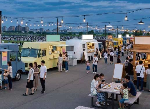 夕暮れの会場に並ぶキッチンカーと来場者