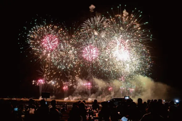 観覧席から夜空を見上げる観客と、頭上に咲く高石超花火